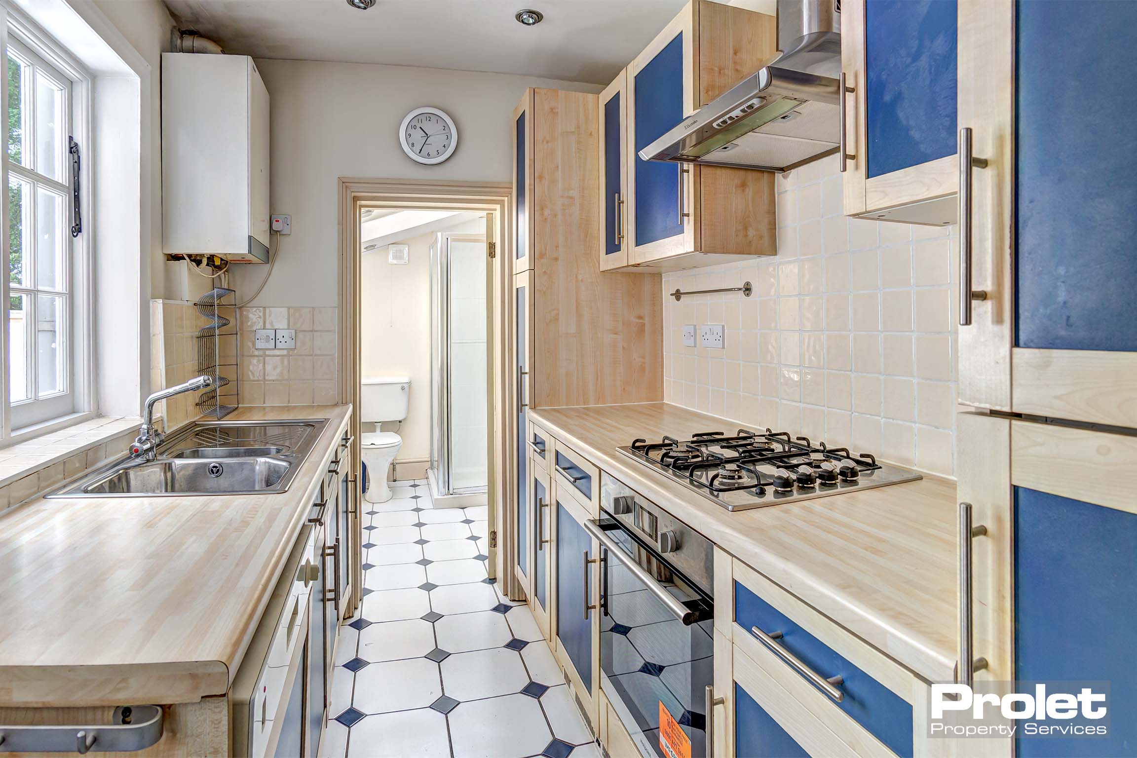 Galley style fitted kitchen with wooden worktops and tiled flooring.