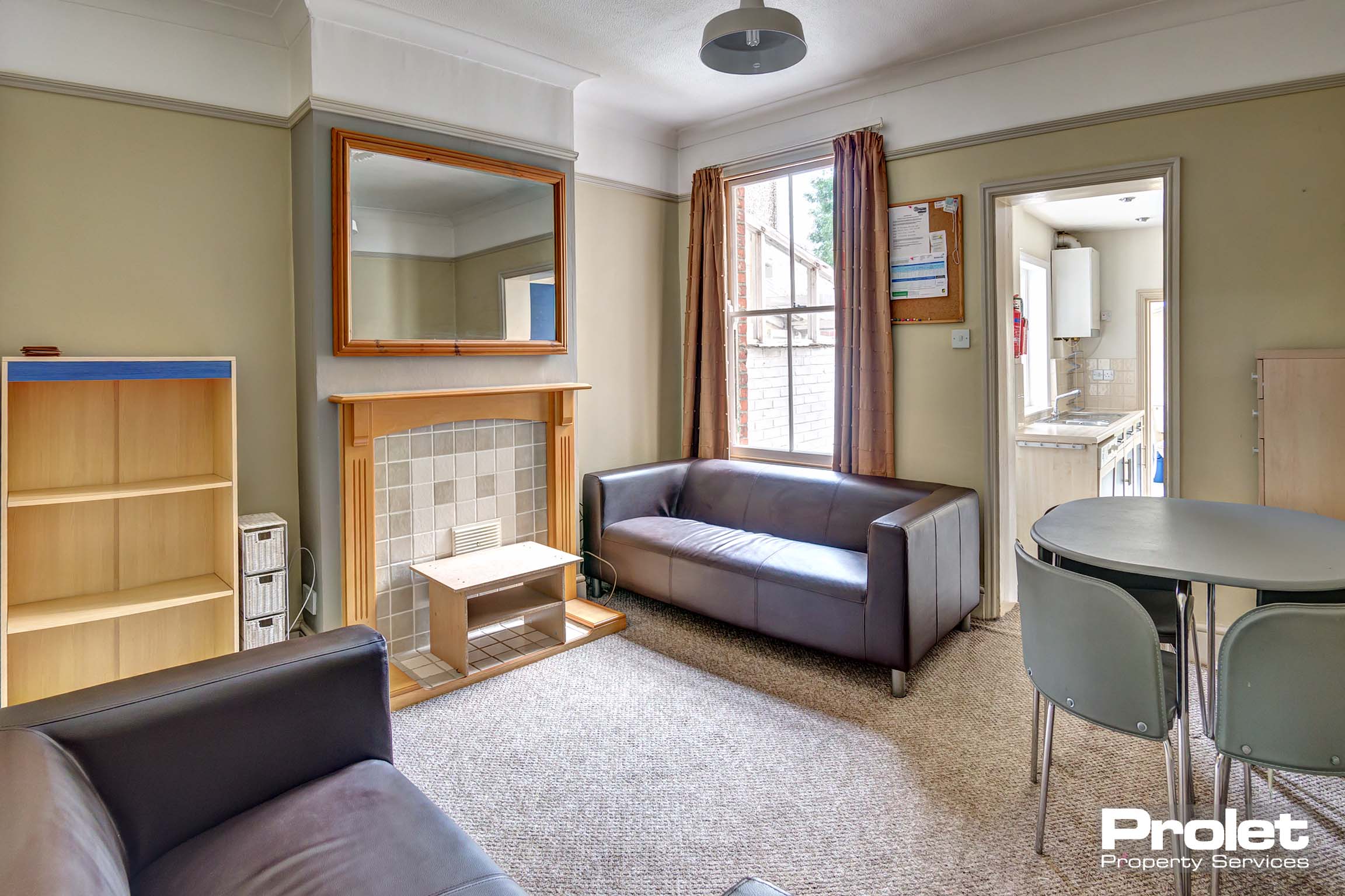 Lounge area with fabric sofas, dining table and a bookshelf.