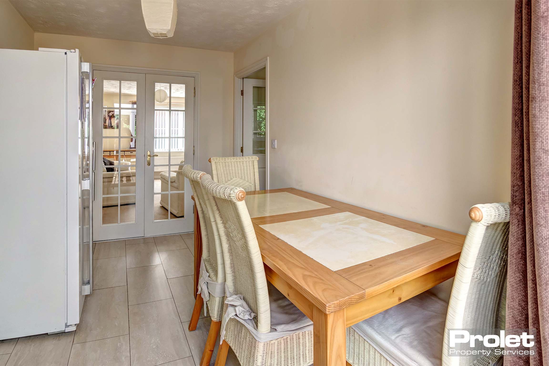 Dining area with tiled flooring and a wooden dining table with four matching chairs.