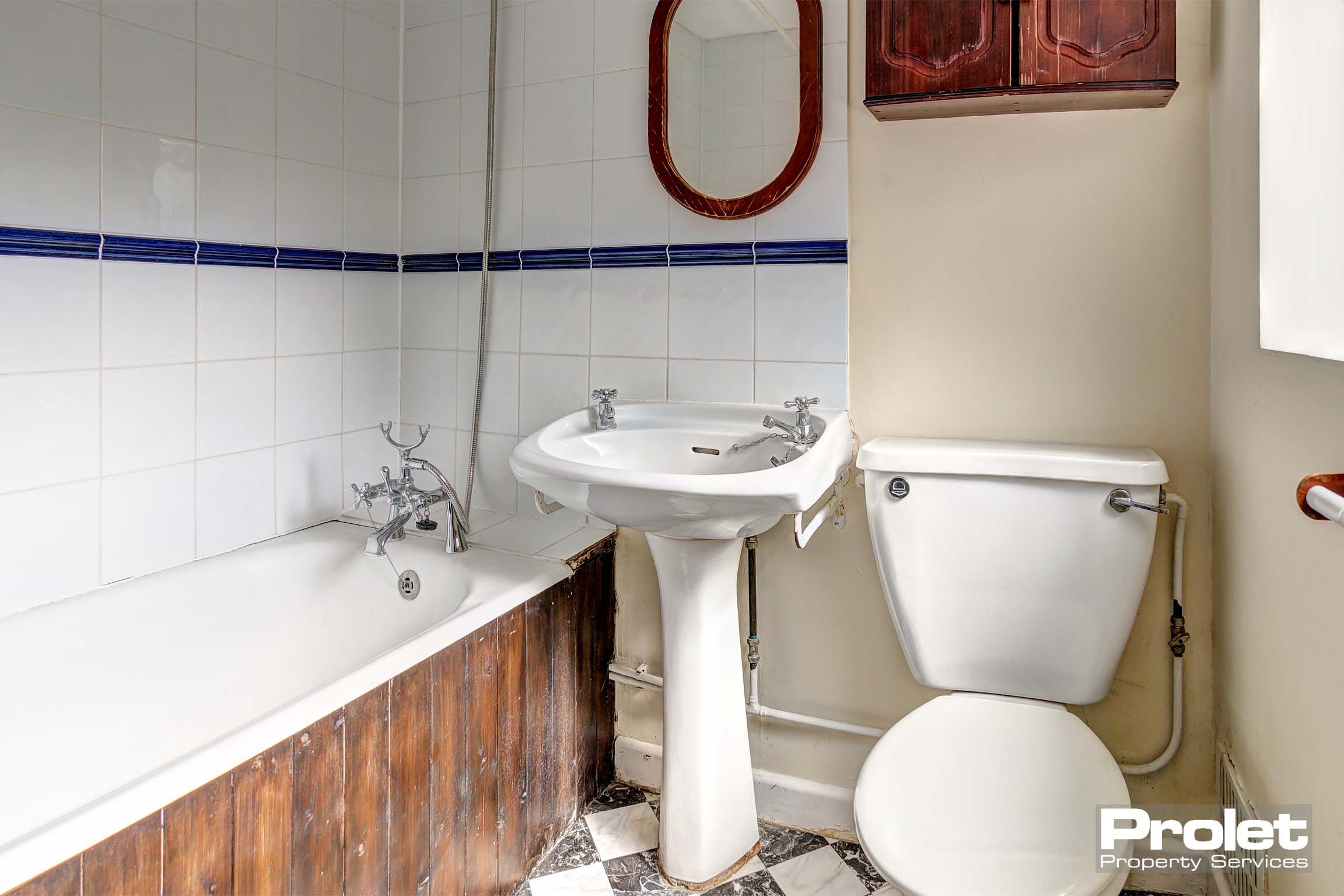 Bathroom with toilet, sink, and shower over bath