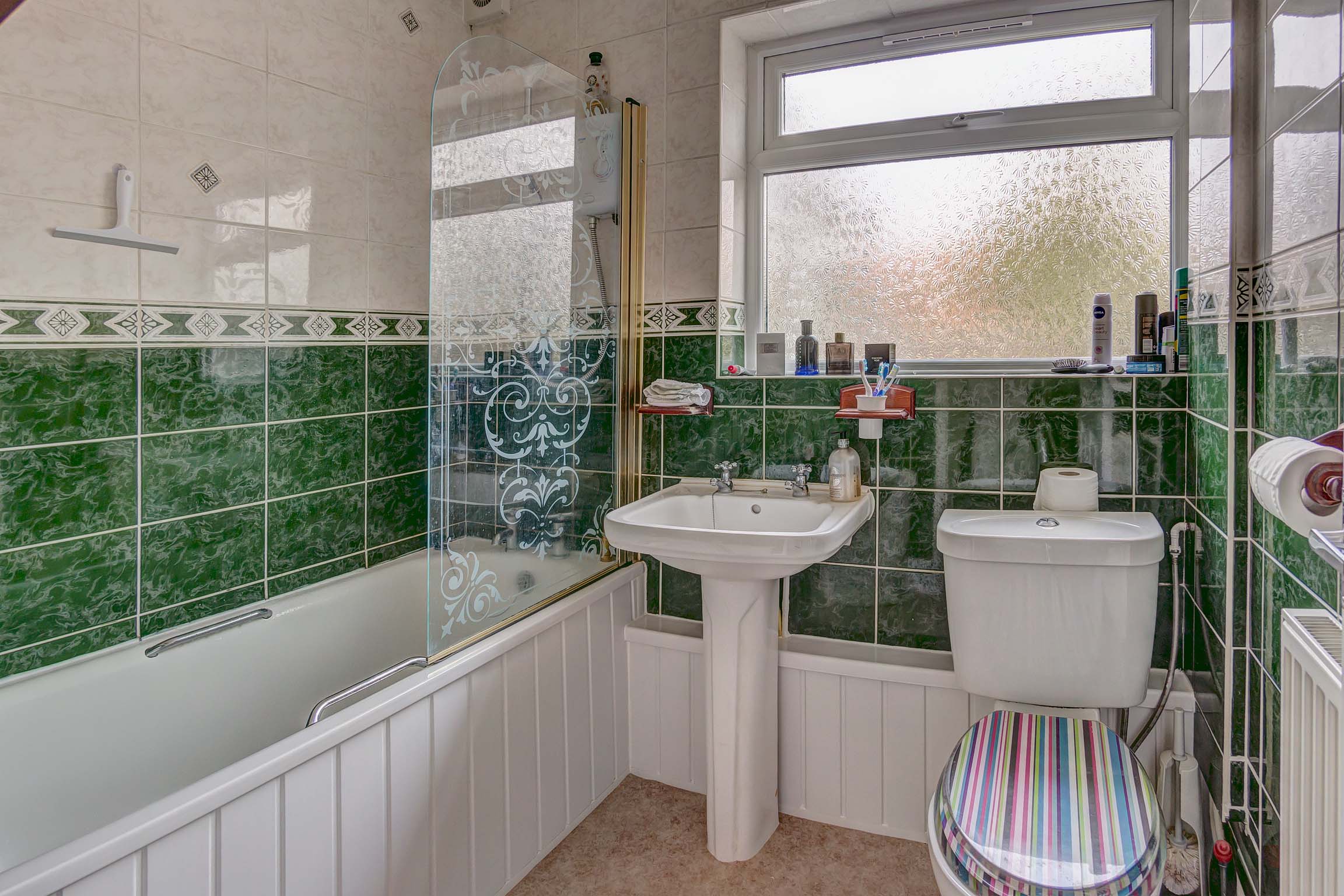 Bathroom with green tiles, bath, toilet, and sink