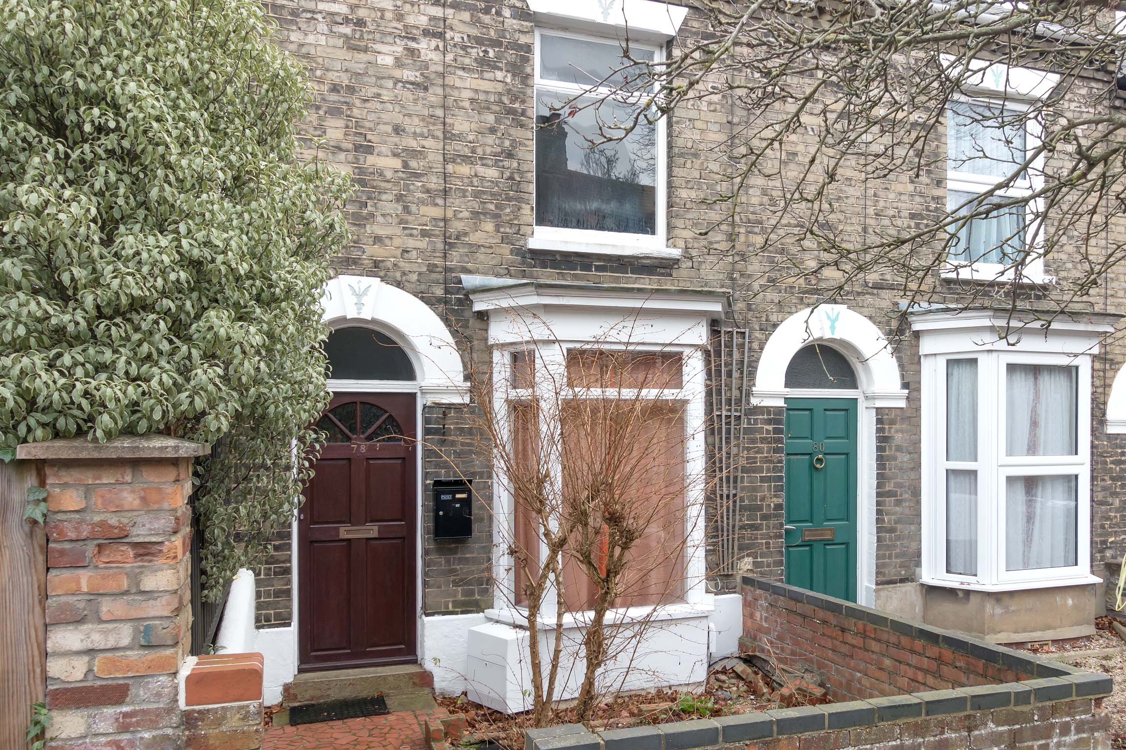 Grey brick terraced house with brown front door