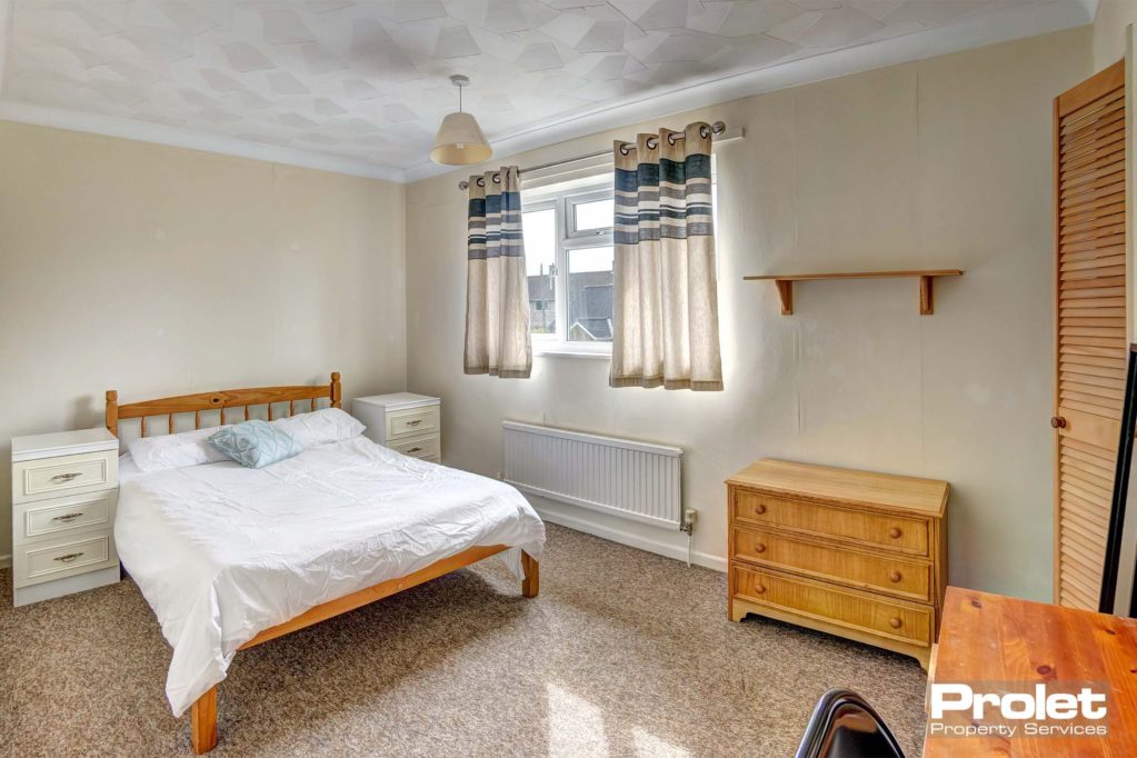 Large double room with wooden bedside table, chest of drawers and built in wardrobe.