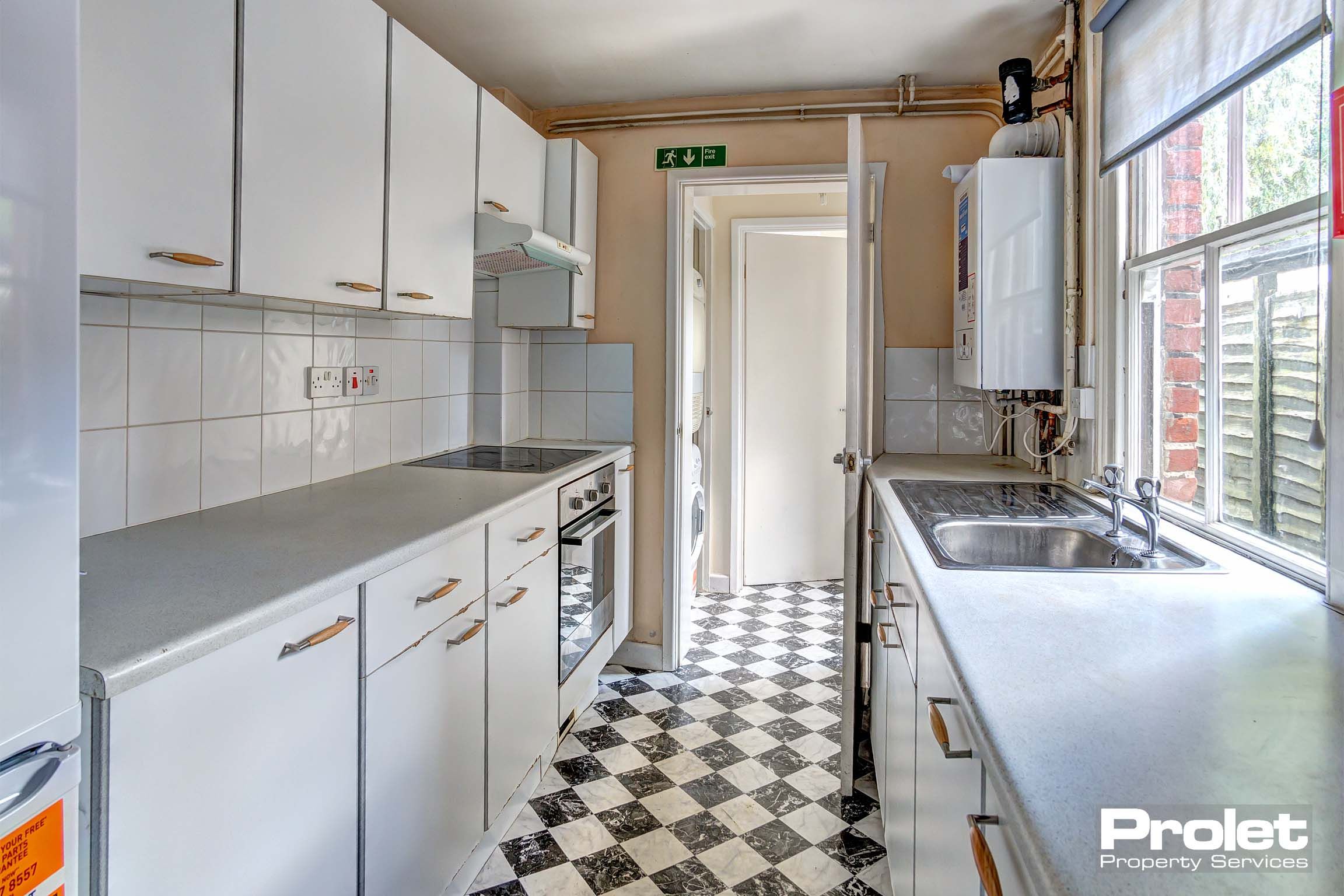 Galley kitchen with white unity and black and white tiled floor