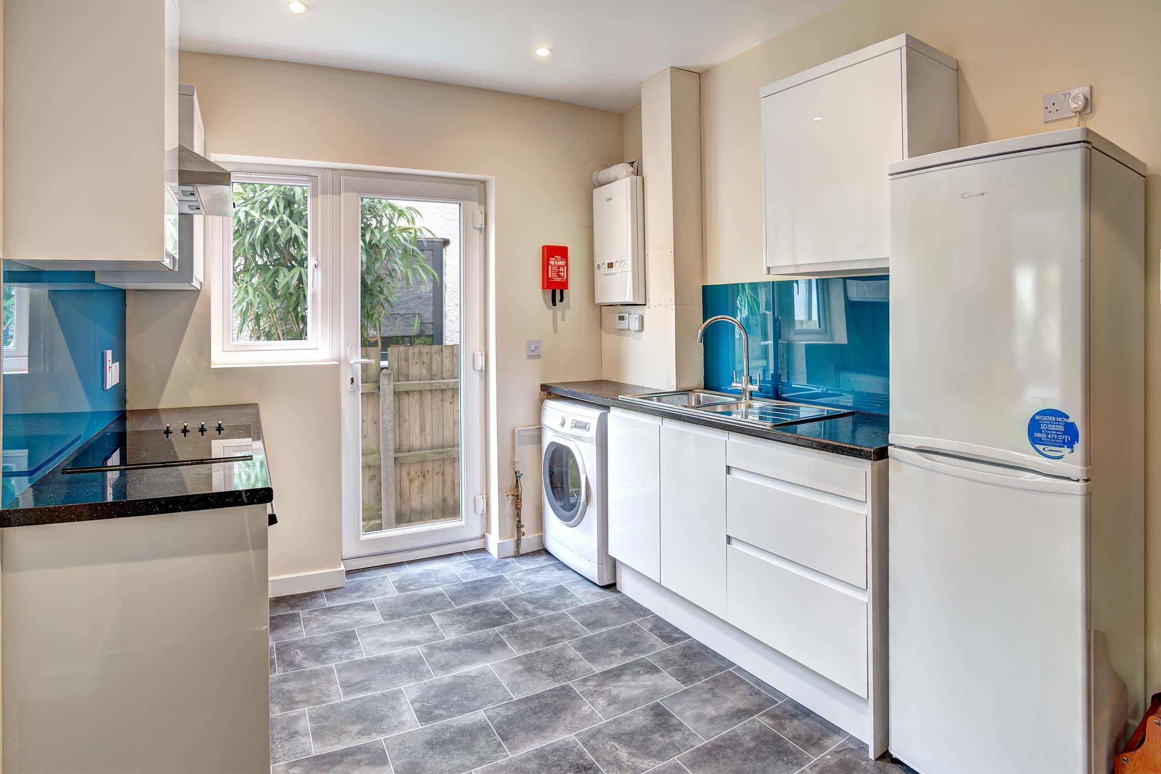 Kitchen with tiled floor, white cabinets, and white goods