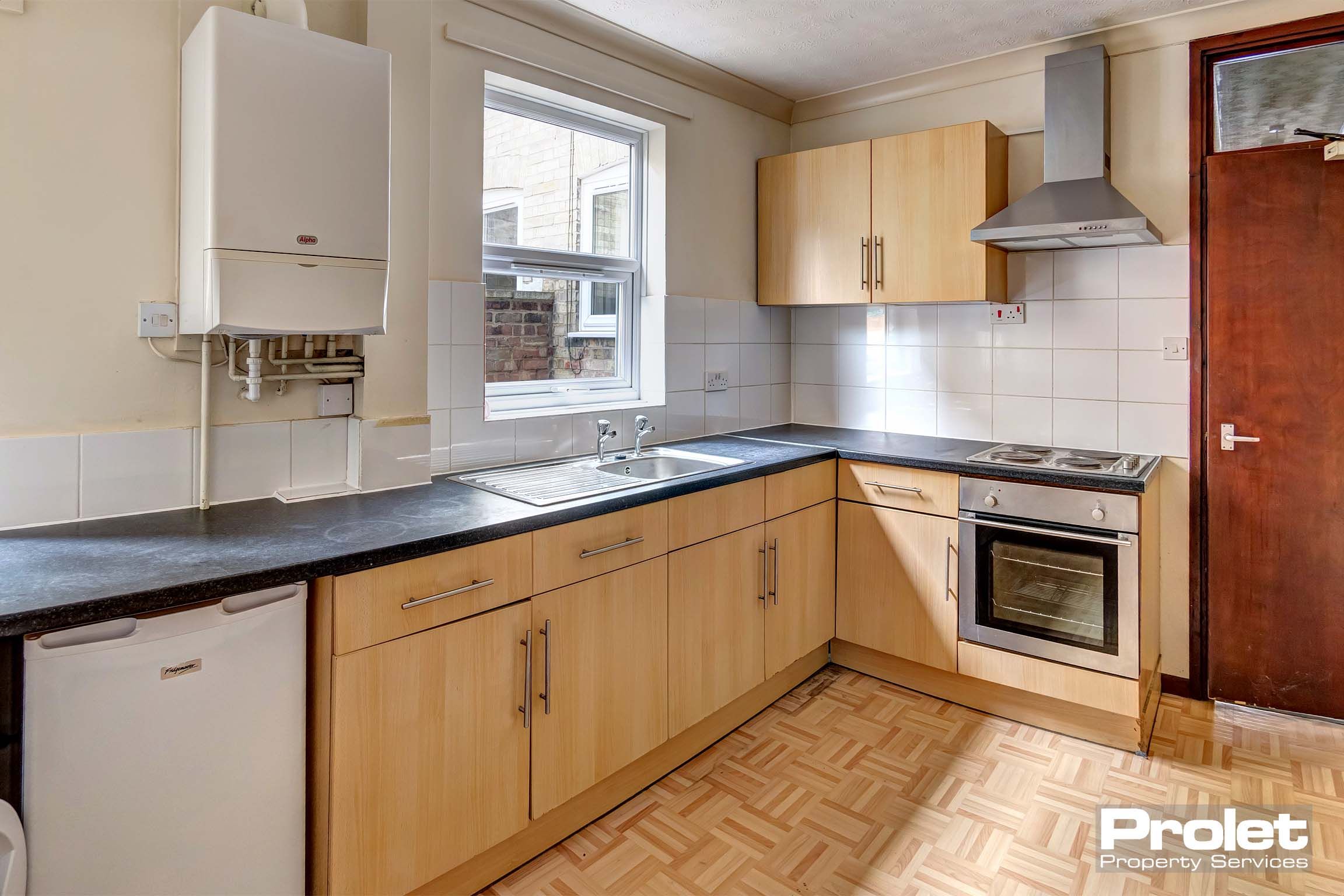 Wooden effect fitted kitchen with oven and extractor fan.