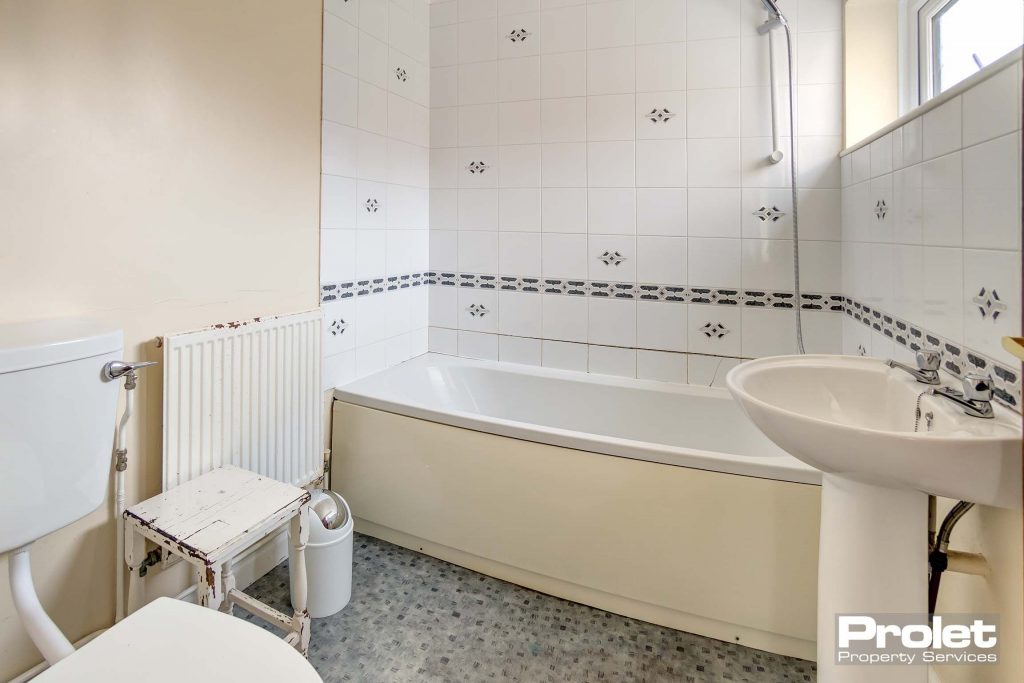 Bathroom with shower over bath, sink, and toilet.