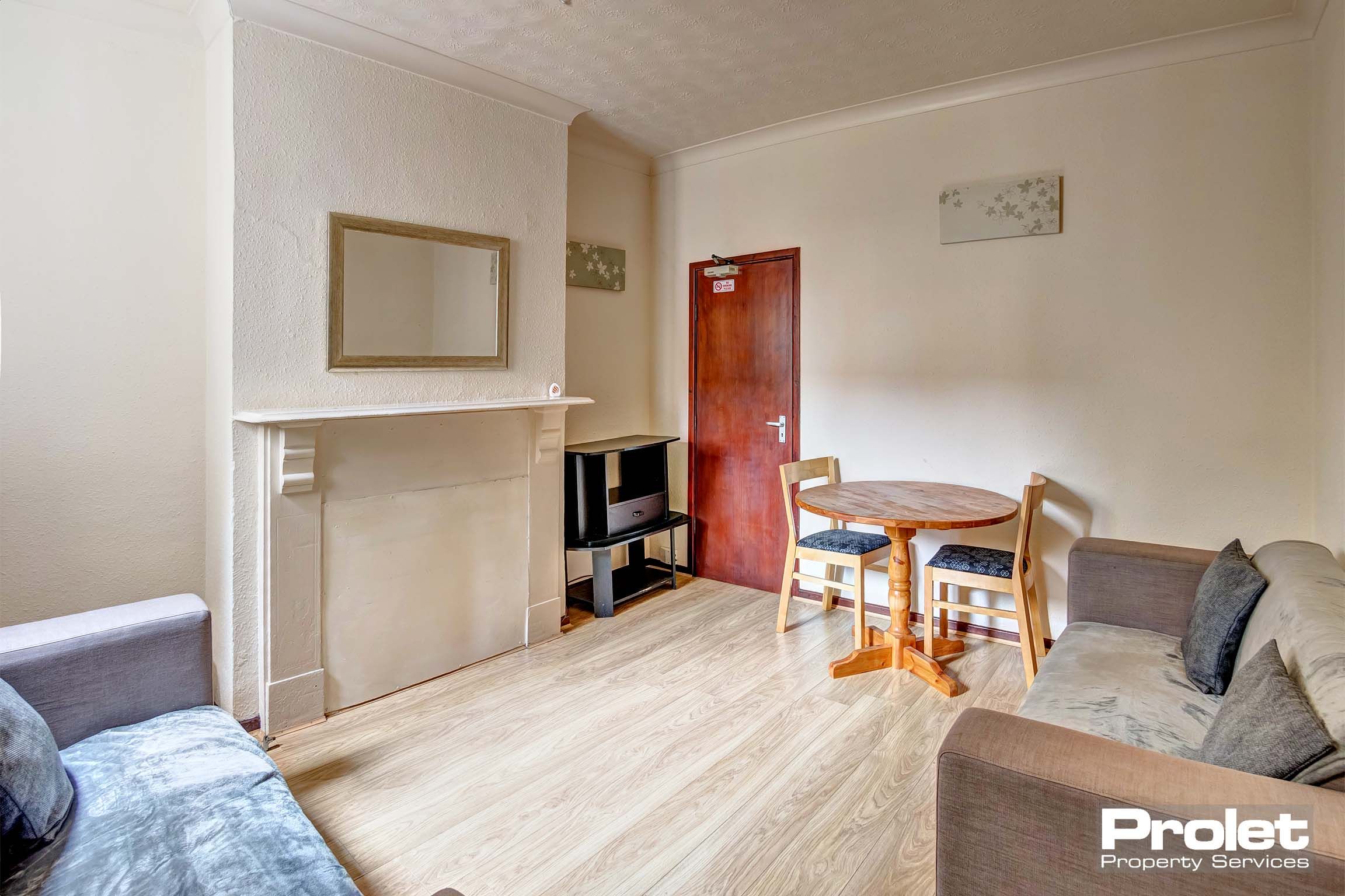 Lounge area with two fabric sofas and a wooden dining table.