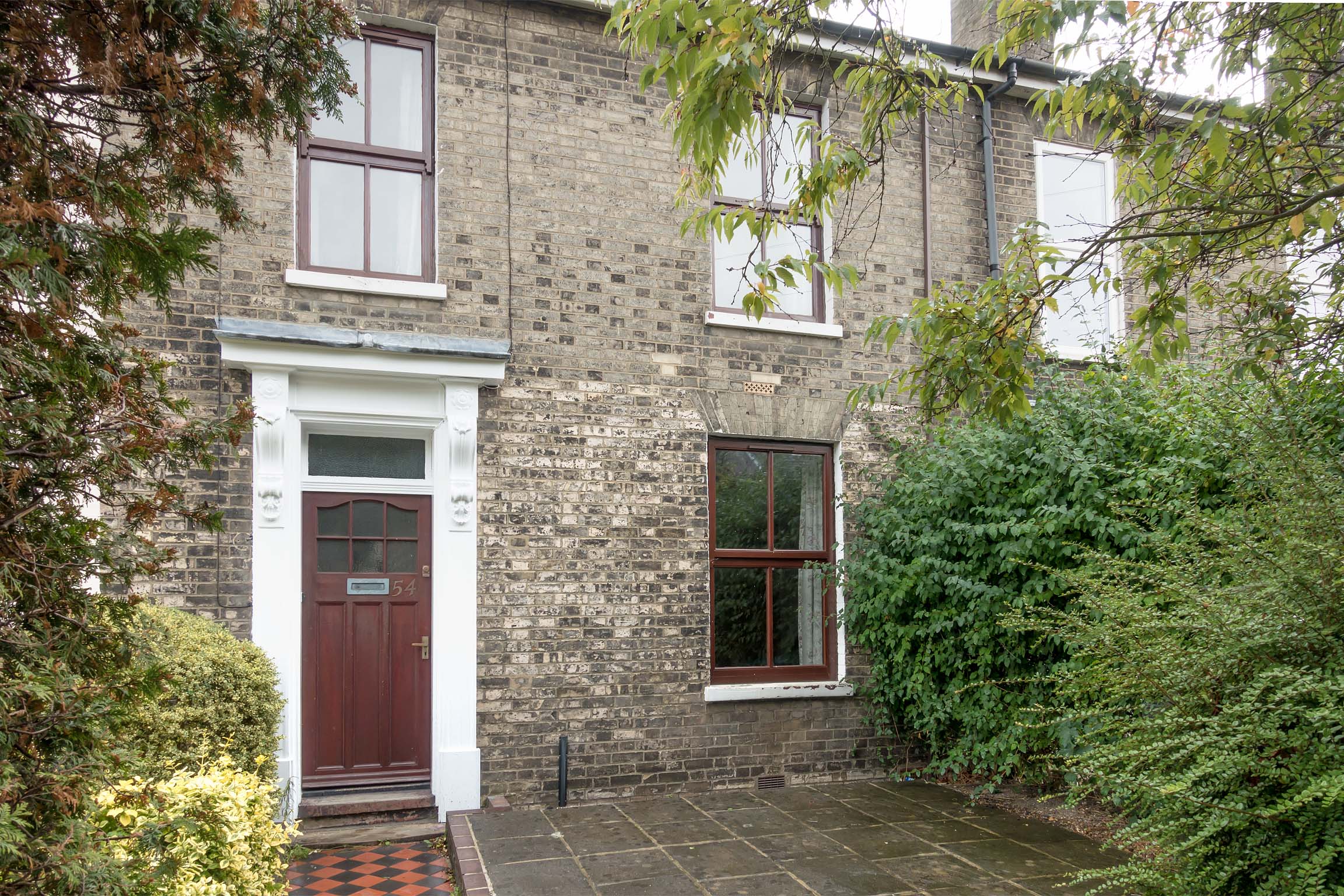 Grey bricked terraced house, with paved front garden