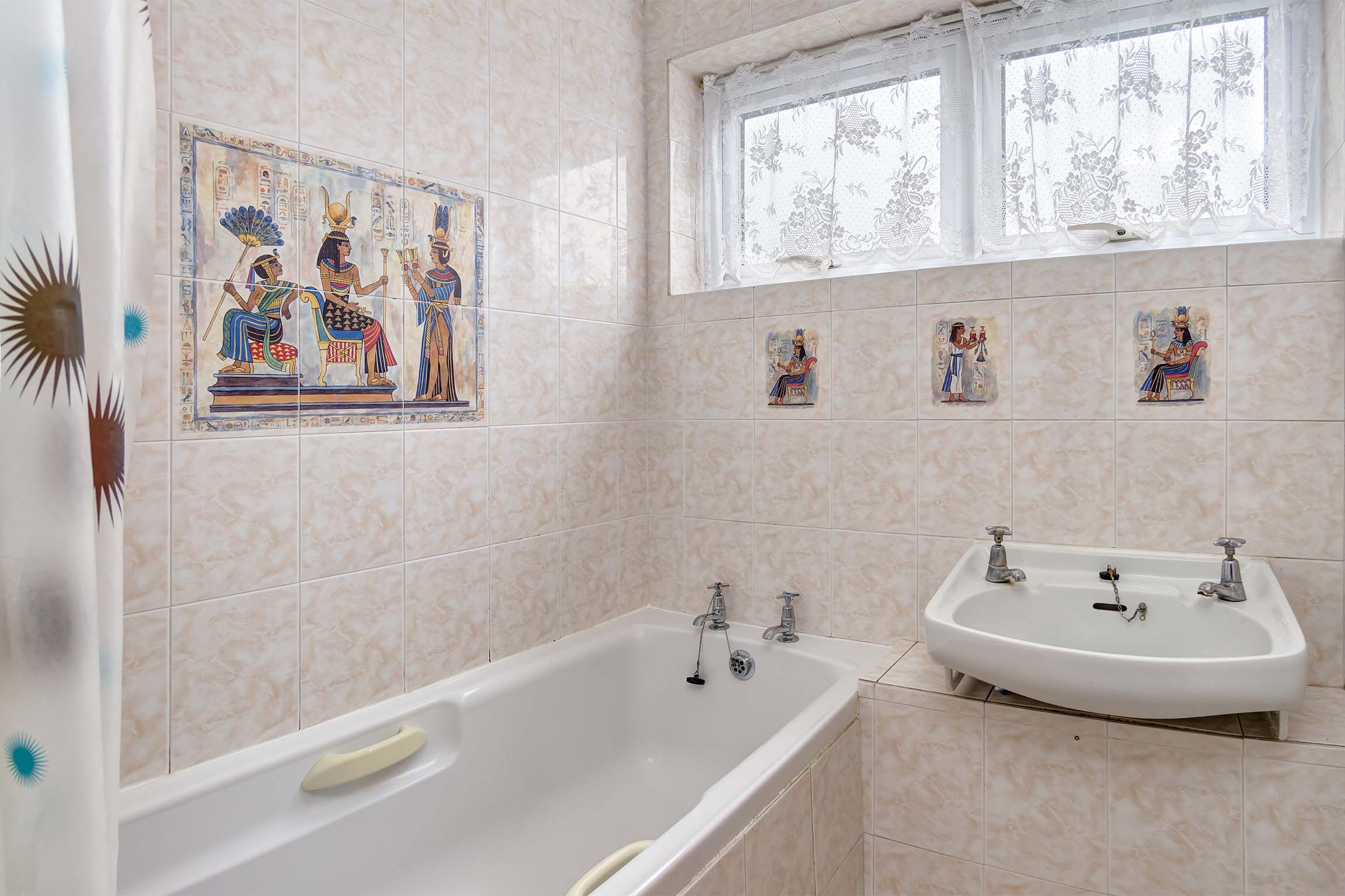 Bathroom with tiled walls, with a white sink and bathtub.