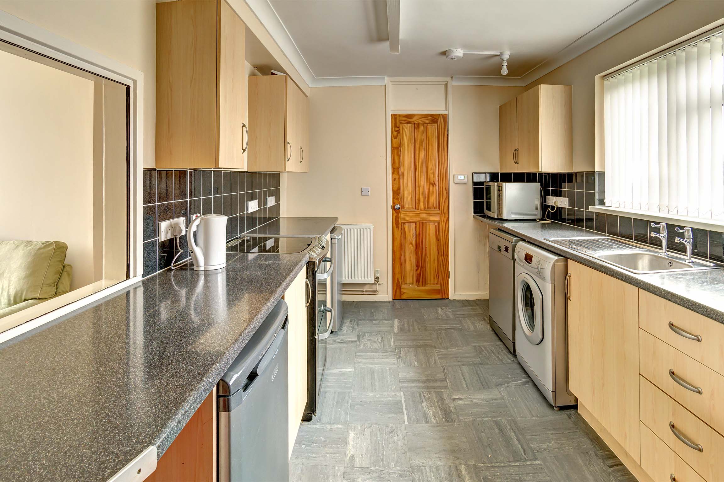 Galley style kitchen with fitted wooden effect units and a black grain worktop.