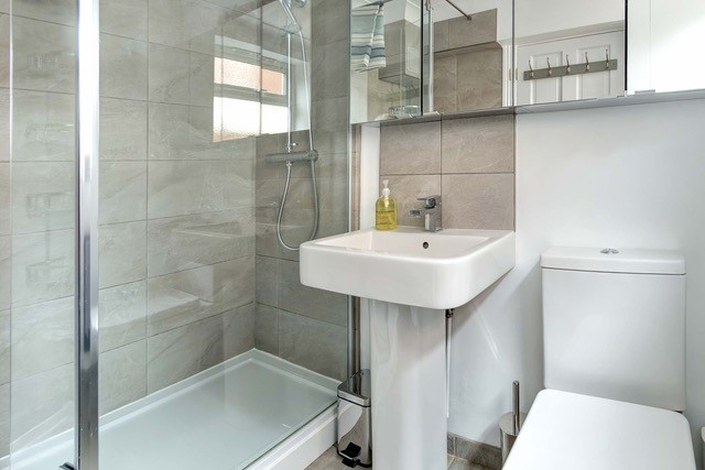 Tiled bathroom with a walk in shower and a modern sink and toilet.