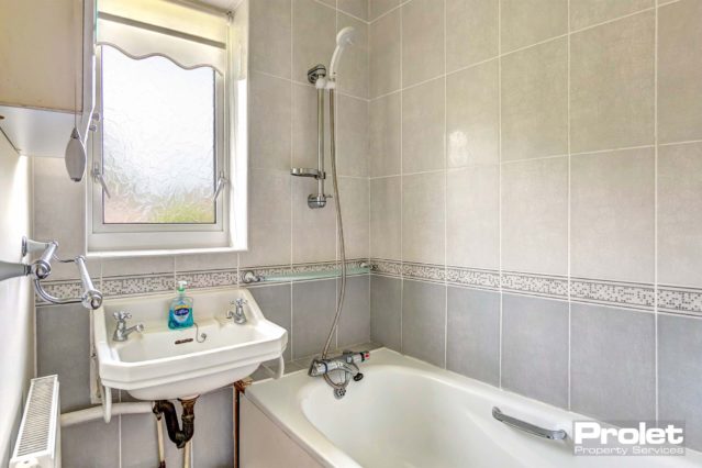 Tiled bathroom with white sink and bath tub.