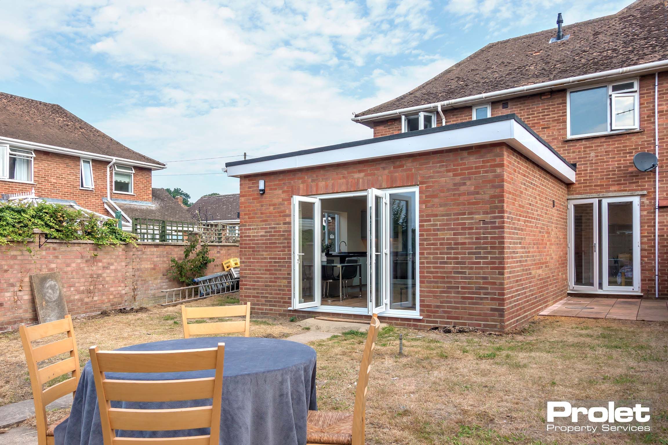 Rear of house, patio doors onto large garden set to lawn