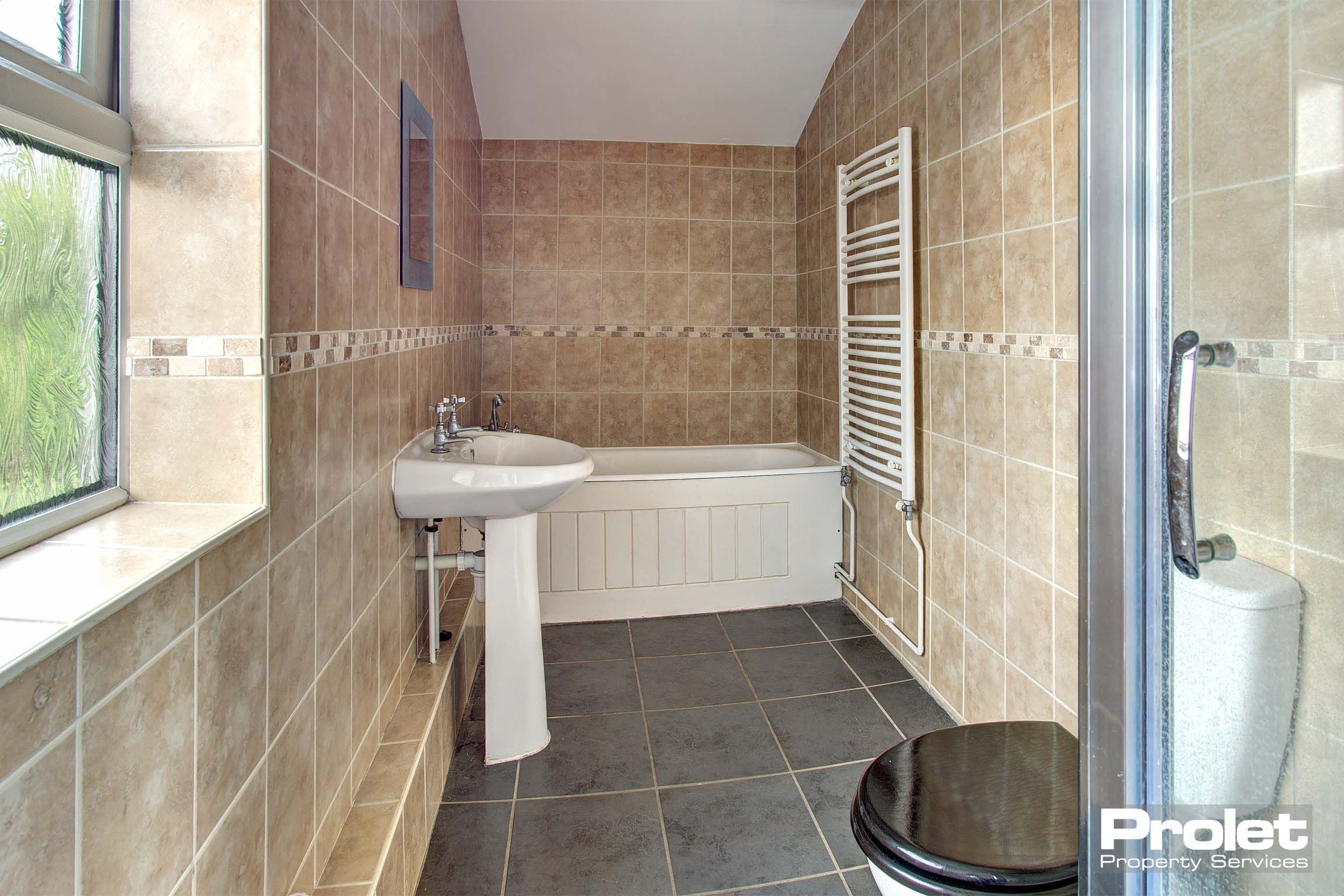 Modern tiled bathroom with shower cubicle, bath, sink, and toilet.