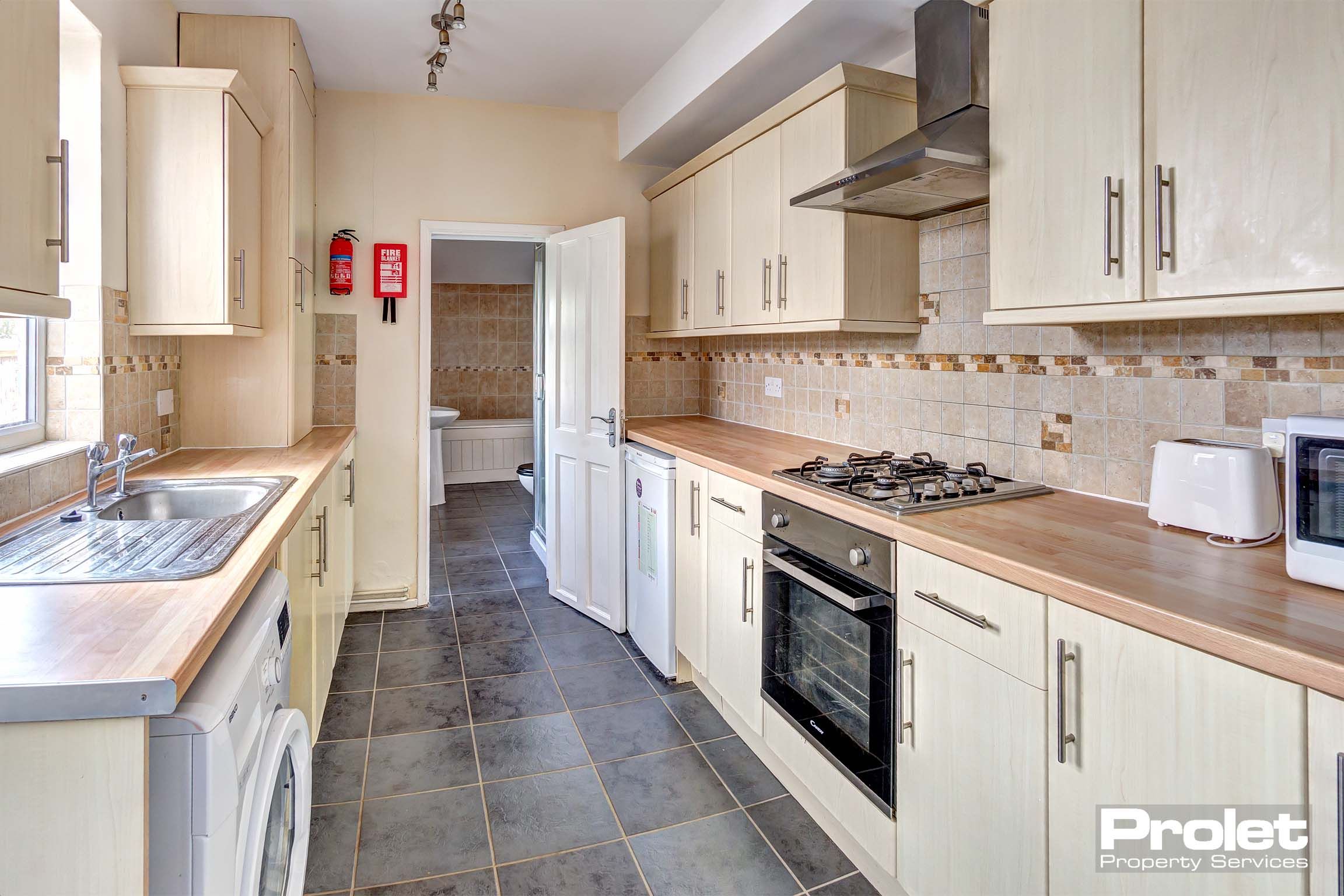 Galley style kitchen with cream units and white goods