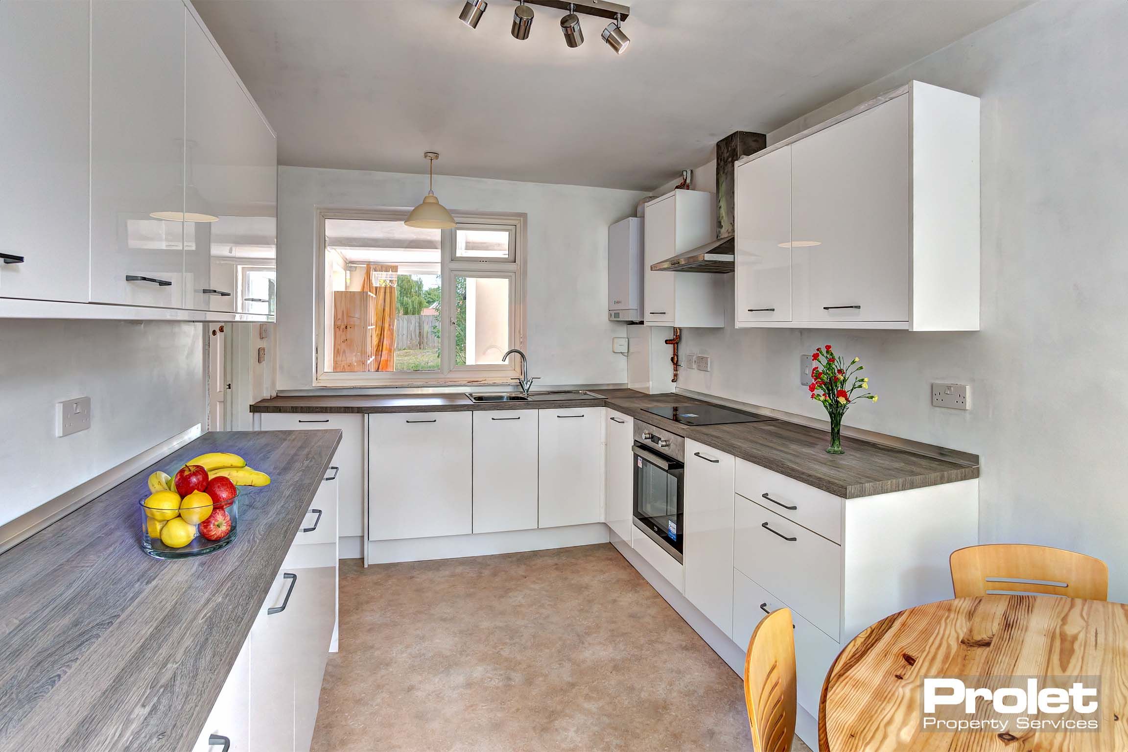 Modern kitchen with white cupboards, grey worktops, with dining table set