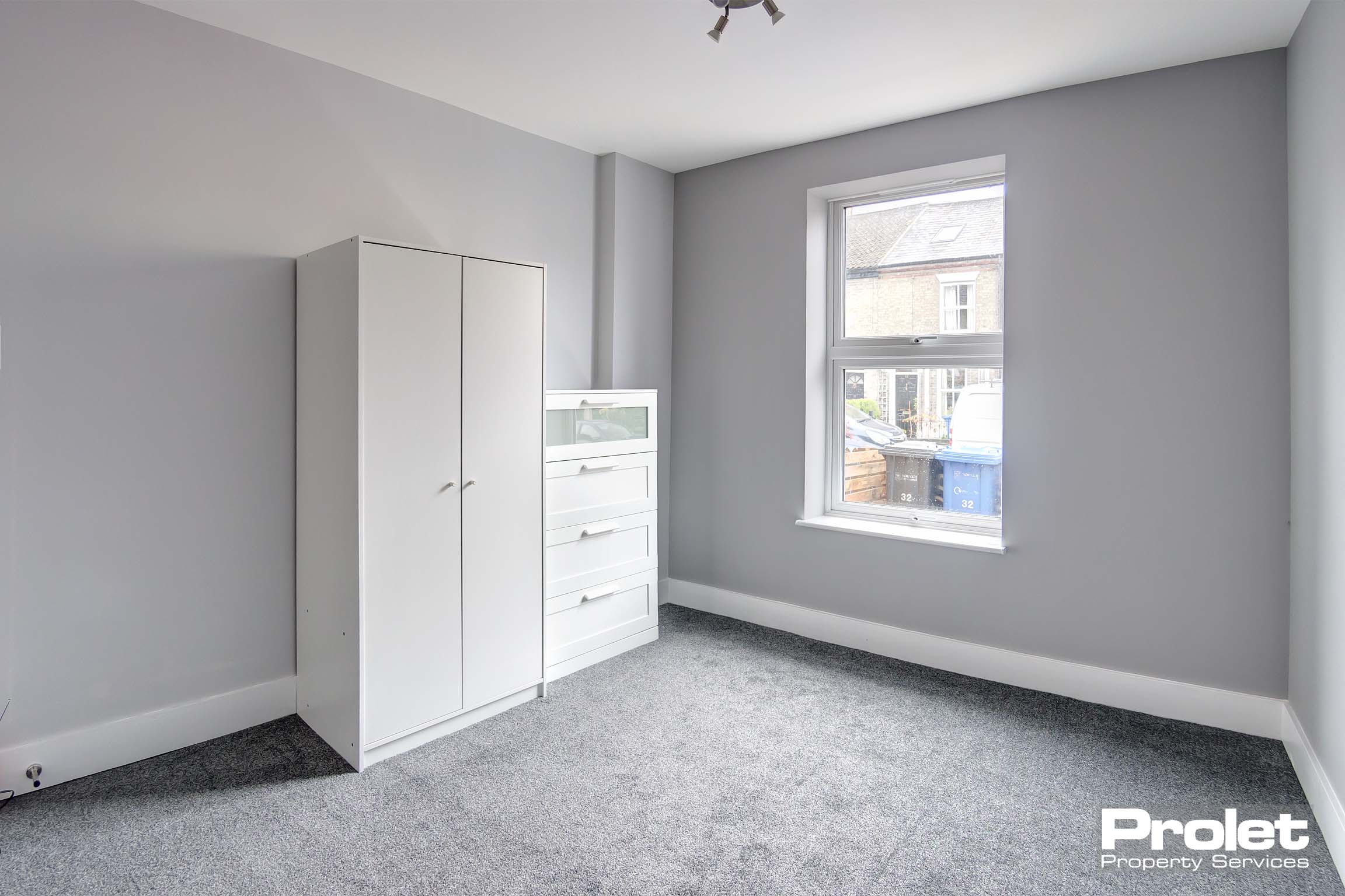 Double bedroom with you white drawers and white wooden wardrobe.