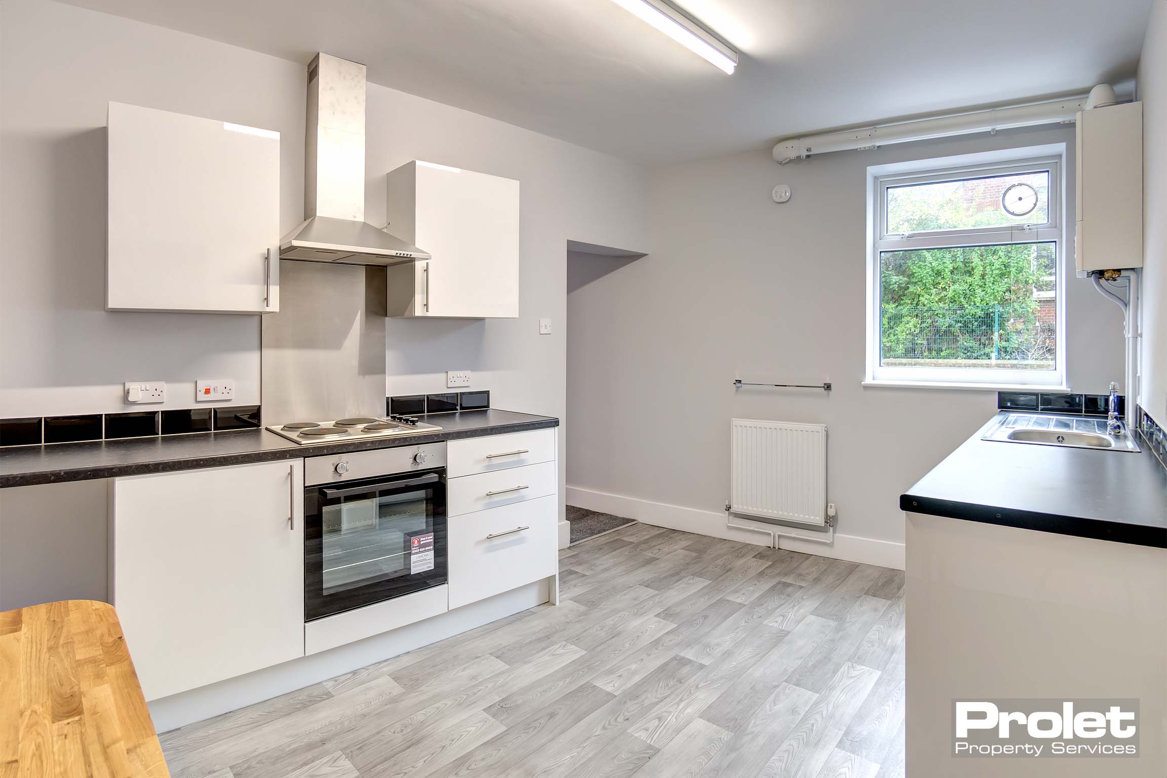 Grey laminate flooring with grey walls. White units and dark grey work tops. Cooker, fridge freezer and washing machine provided.