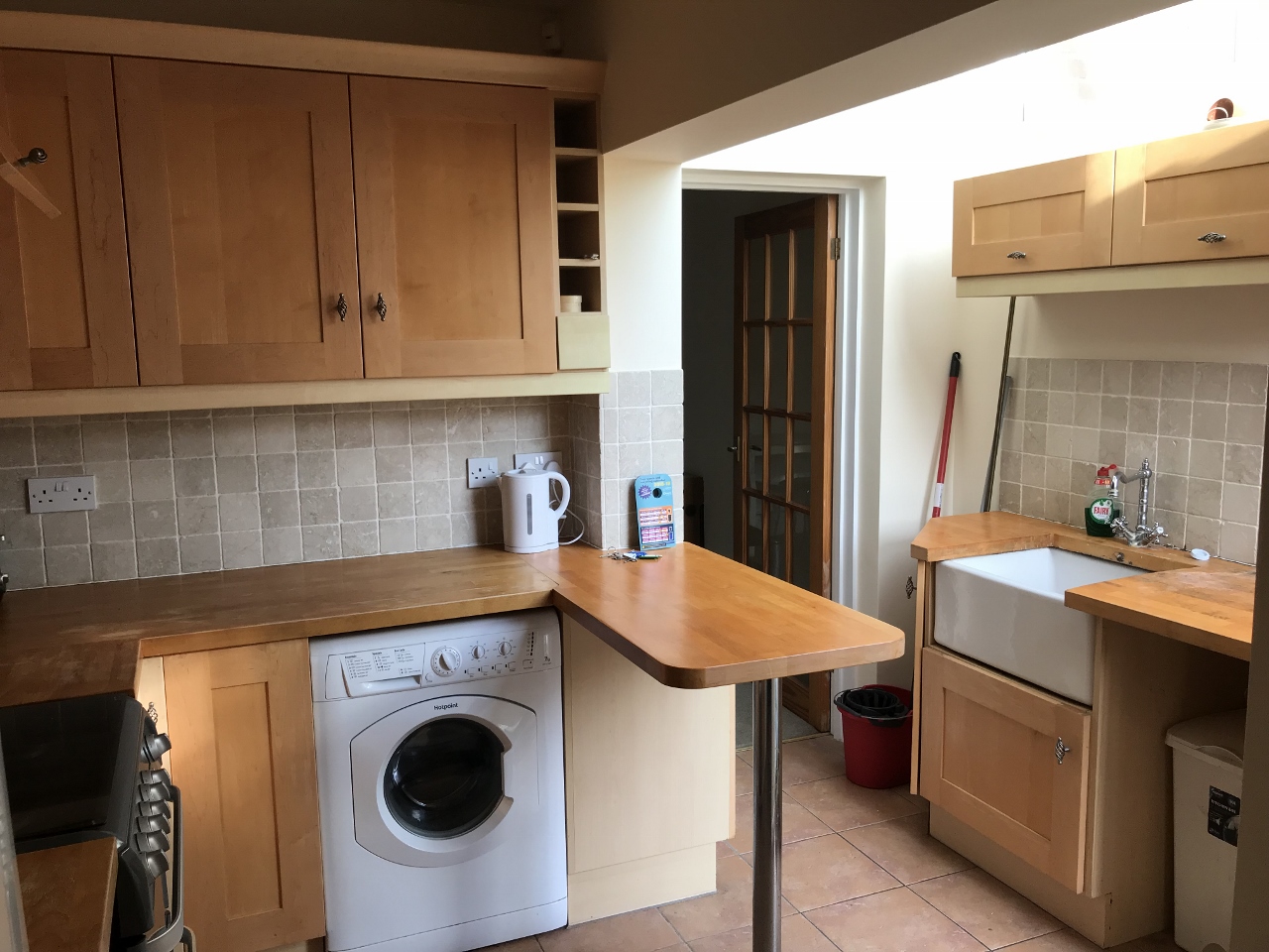 Kitchen with wooden cabinets and worktops, breakfast bar, large appliances and skylight