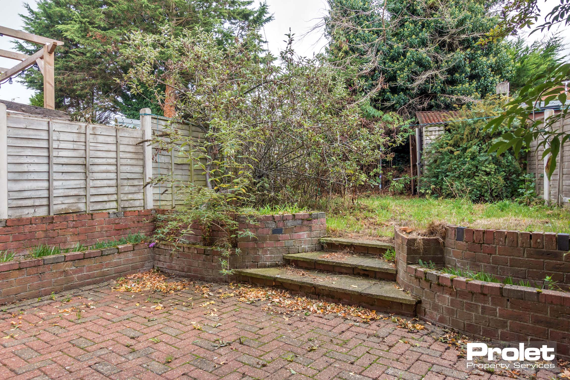 Back garden with steps leading to lawn a lawn and patio