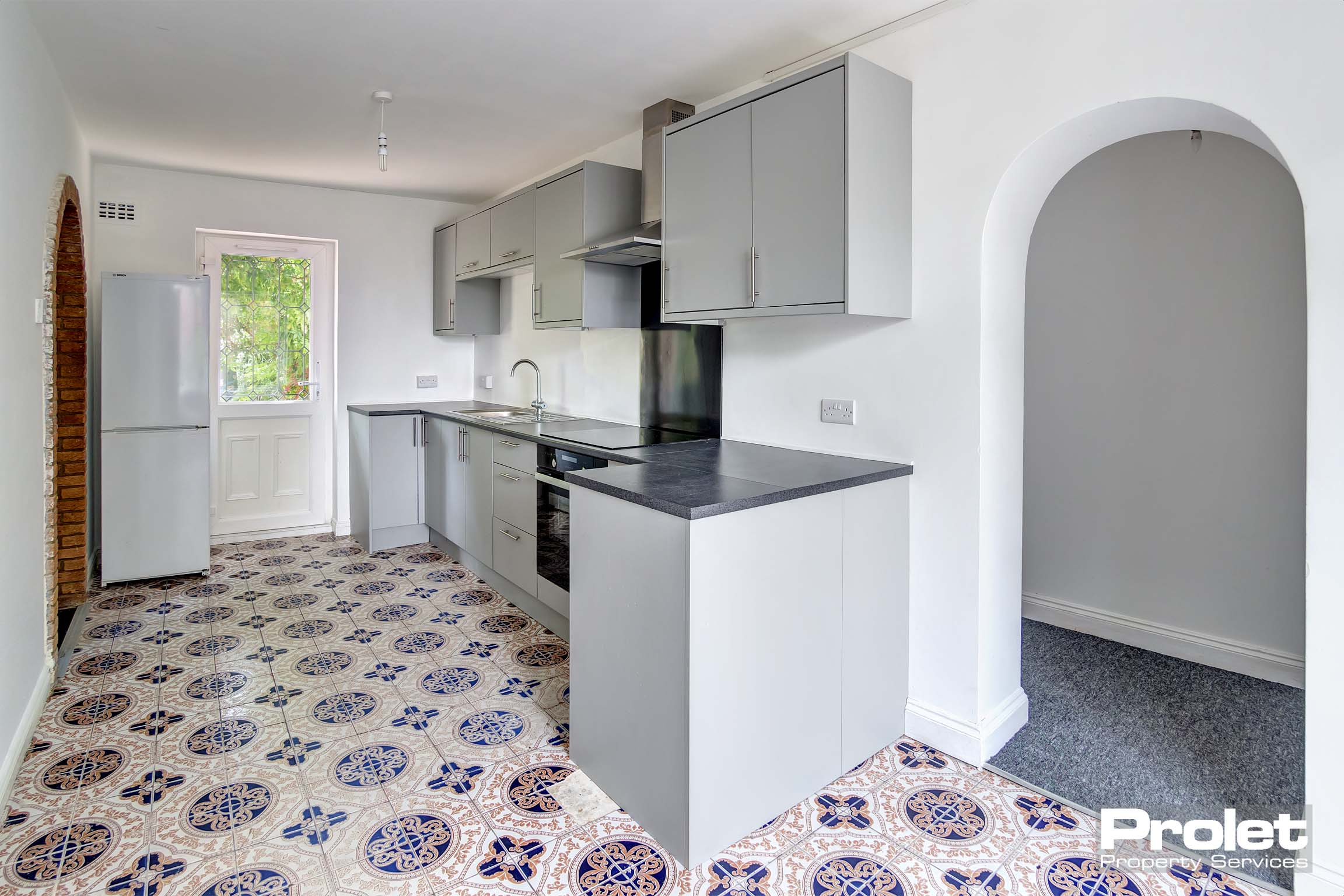 Modern kitchen with grey fittings and tiled floor.