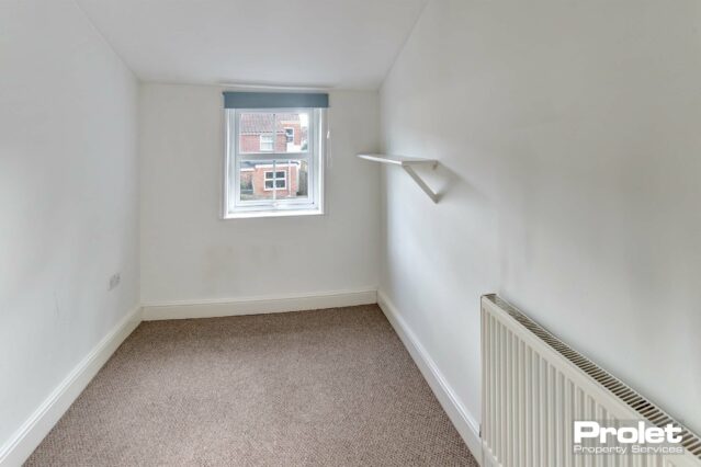 Back bedroom at rear of property off landing. Small corridor with built in shelves and hanging rail with step down to bedroom.