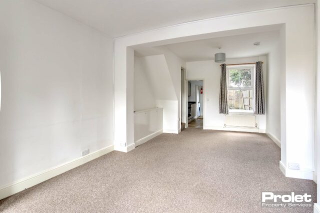 Large open plan lounge/diner with white walls and light brown carpets.