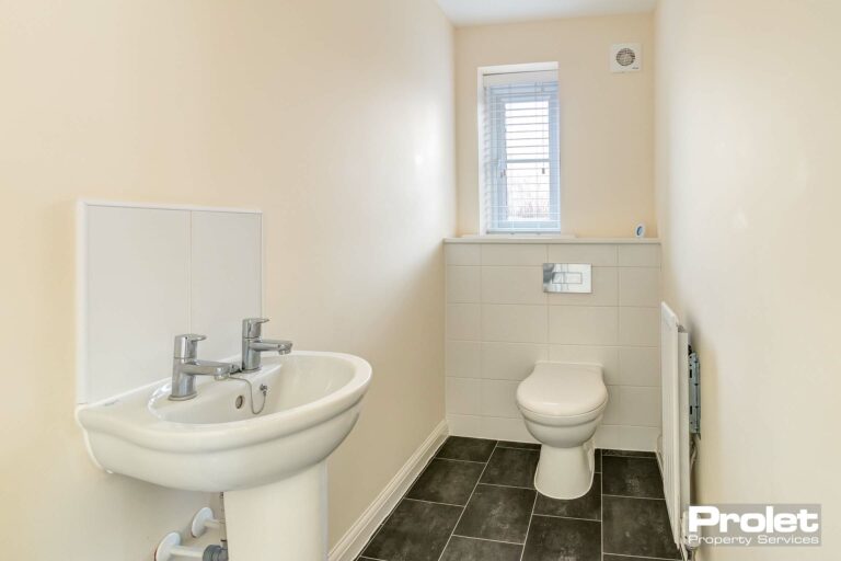 Magnolia walls, grey floor and white toilet and sink.