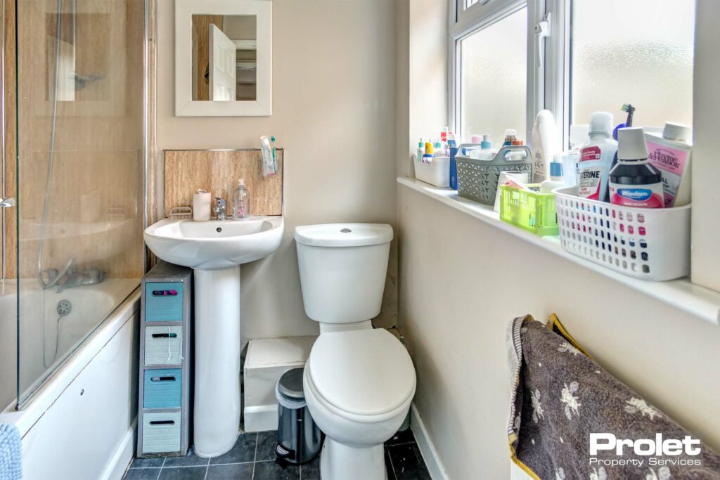 Bathroom with toilet, sink, and shower over bath